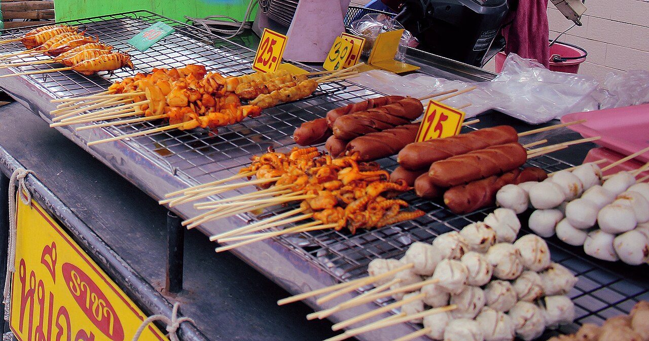 Bangkok street food vendor cooking pad thai in a wok over open flame