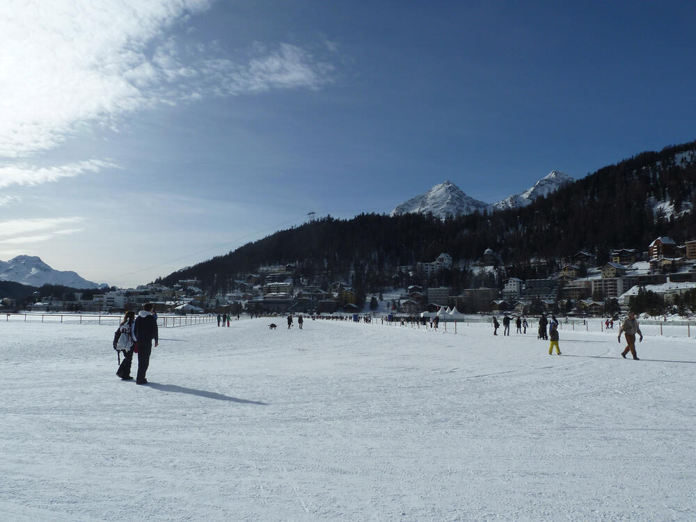 People walking on frozen Lake St. Moritz below the town in late January